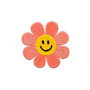 May include: A pink flower with a yellow smiley face in the center. The flower has eight petals and is embroidered.