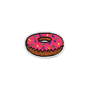 Könnte beinhalten: Rosa glasierter Donut mit bunten Streuseln, gestickt auf einem weißen Stoff-Patch.