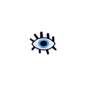 May include: A black and white embroidered eye with a blue iris and white pupil. The eye is surrounded by eyelashes.