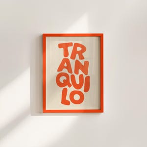 May include: Orange framed art print with the word "TRANQUILO" in large, orange, bubble letters. The background is a light beige color. The frame is a bright orange color and is hanging on a white wall.