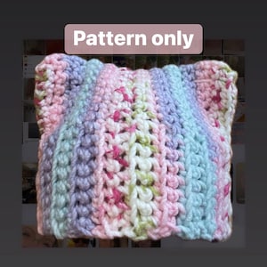 May include: A crochet pattern for a striped hat with cat ears. The hat is made with a variety of colors, including pink, purple, blue, and white.