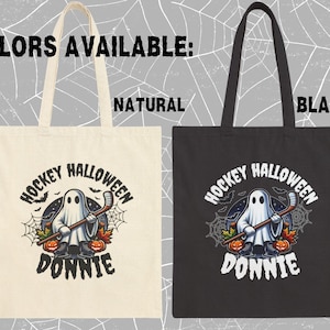 K&ouml;nnte beinhalten: Zwei Tragetaschen, eine naturfarbene und eine schwarze, mit einer Grafik eines Geistes, der Schlittschuhe tr&auml;gt und einen Hockeyschl&auml;ger h&auml;lt. Der Text lautet HOCKEY HALLOWEEN DONNIE, umgeben von Spinnweben, Flederm&auml;usen und K&uuml;rbissen.