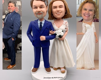 May include: A wedding cake topper featuring a bride and groom in a blue suit and white dress. The bride is holding a bouquet of white flowers. The cake topper is on a white base with the text "Jennifer & Ken 2-24-24".