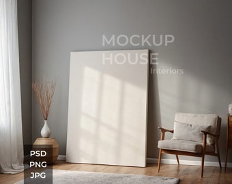 May include: A white canvas mockup frame leaning against a gray wall with a wooden chair and a vase with dried branches in the foreground. The text "MOCKUP HOUSE Interiors" is visible at the top of the frame.