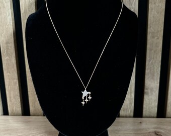 May include: A gold chain necklace with a star-shaped pendant and three smaller star charms hanging from it. The necklace is displayed on a black velvet mannequin.