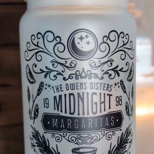 May include: A white frosted glass with a bamboo lid and a black and white design. The design features a crescent moon, stars, and the text "The Owens Sisters 19 Midnight 98 Margaritas Salem, MA".