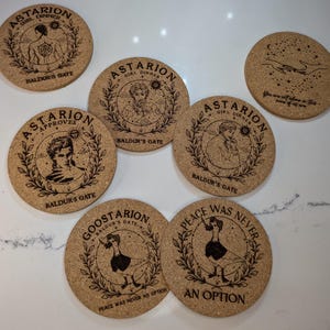 May include: Six cork coasters with laser-etched designs featuring characters and text from the video game Baldur's Gate 3. The coasters feature a variety of designs, including a character named Astarion, a goose, and the text "Peace Was Never An Option".