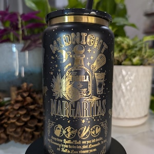 May include: Black and gold stainless steel tumbler with a design of a bottle of tequila, limes, and a margarita glass. The tumbler has the text "Midnight Margaritas" and a quote about throwing salt over your left shoulder, planting rosemary, and falling in love.