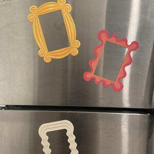 May include: Three decorative picture frames in the image. The top left frame is gold with ornate detailing. The top right frame is pink and orange with a wavy design. The bottom frame is white with a wavy design.
