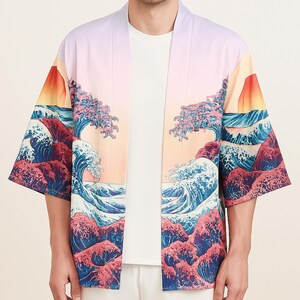Puede incluir: Un kimono rosa claro y blanco con un estampado de olas azules y rojas. El kimono tiene un diseño japonés tradicional con una puesta de sol y una escena de montaña.