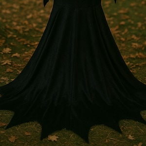 May include: A long, black dress with a flared skirt and a unique hemline. The hemline features pointed edges, creating a batwing-like design. The dress is made of a soft, flowing fabric.