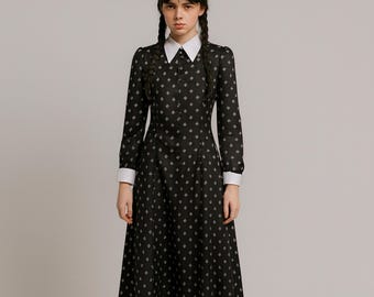 May include: A black long-sleeve dress with a white collar and cuffs. The dress features a diamond pattern and a button-down front. The dress is knee-length and has a fitted bodice that flares out at the waist.