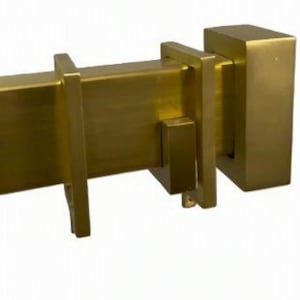 May include: A square-profile curtain rod in a brushed brass finish, featuring a rectangular end cap and two matching square brackets that slide over the rod. The metal hardware has a smooth, matte metallic texture and a uniform gold-toned color.