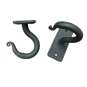 May include: Two black metal hooks with a decorative swirl design. The hooks are mounted on a rectangular metal plate.