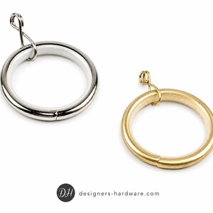 May include: Two circular curtain rings with attached eyelets. One ring features a polished silver-tone finish with a white inner lining, while the other ring has a brushed gold-tone finish. The logo DH designers-hardware.com is at the bottom.