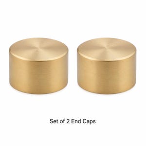 May include: A set of two cylindrical end caps with a brushed gold finish. Each cap features a flat circular top and smooth vertical sides. The text "Set of 2 End Caps" is printed in black below the two identical metallic objects.