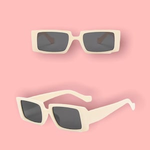 May include: Two pairs of white rectangular sunglasses with dark lenses. The sunglasses are on a pink background.