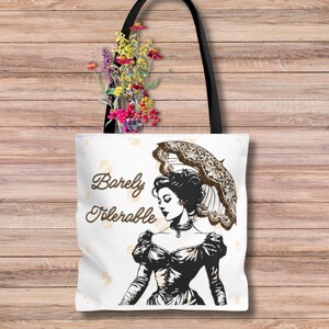 May include: White tote bag featuring a black and white illustration of a woman in a dress holding an umbrella. The text "Barely Tolerable" is printed in brown on the bag.
