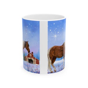 May include: A white ceramic mug with a winter scene featuring two brown horses in a snowy field with a red barn. The sky is blue with white stars and a single bright star.