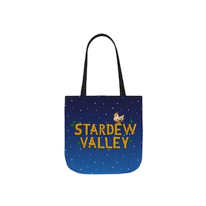 Puede incluir: Un bolso tote con asas negras y un fondo degradado azul. El bolso presenta el texto "STARDEW VALLEY" en dorado, con un pollo pixelado y hojas verdes. Estrellas blancas están dispersas por el fondo.