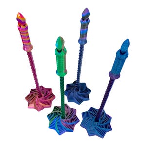 May include: Five colorful, decorative objects with a star-shaped base and a twisted stem. Each has a different color scheme, including pink, green, blue, and rainbow hues. The tops are shaped like crystals.