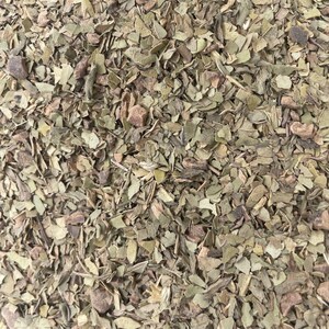Peut inclure: Gros plan sur des feuilles et tiges de yerba mat&eacute; s&eacute;ch&eacute;es. L'image pr&eacute;sente un m&eacute;lange de morceaux verts et bruns, avec des textures et des formes vari&eacute;es. Les feuilles semblent coup&eacute;es ou bris&eacute;es, cr&eacute;ant un aspect naturel et terreux.