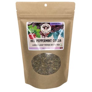 Peut inclure: Un sac en papier brun contenant du th&eacute; yerba mat&eacute; en feuilles en vrac avec une fen&ecirc;tre transparente. L'&eacute;tiquette indique "Hot Peppermint Cocoa" et "Sans caf&eacute;ine". Le sac pr&eacute;sente un logo avec un visage de femme et une tasse de cacao.