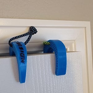 May include: Two blue door stops with a black and white rope attached to one. The door stop on the left has the word "Mission" printed on it.