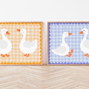 May include: Two printable wall art prints featuring white geese on a checkered background. One print has a yellow and orange checkered background, and the other print has a blue and purple checkered background.