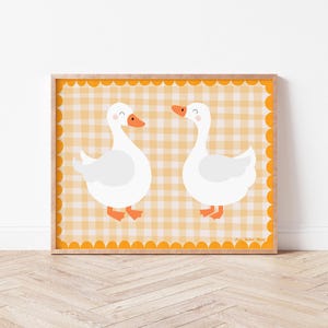 May include: A printable art print featuring two white geese with orange beaks and feet on a yellow and white gingham background.