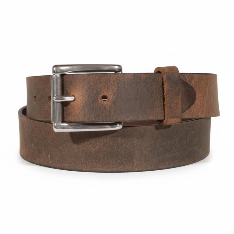 May include: A brown leather belt with a silver-colored buckle. The belt is made of a distressed leather material, and the buckle is rectangular. The belt is wrapped around itself, showing the buckle and the belt loop.
