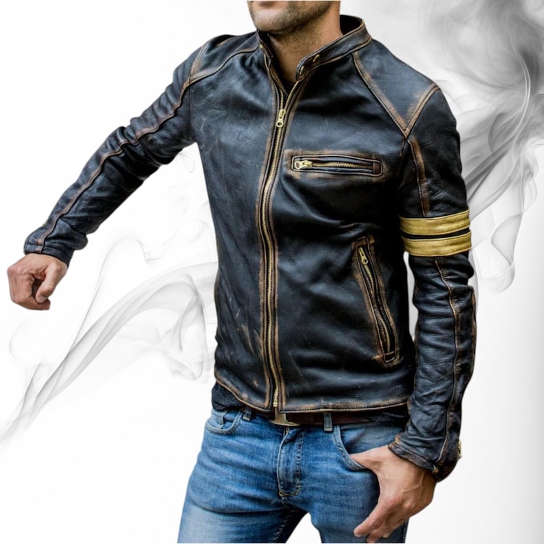 May include: Black leather jacket with a distressed finish, featuring a stand-up collar, multiple zippered pockets, and gold-colored accents. The jacket has gold stripes on the left sleeve and a front zipper closure. The model is wearing blue jeans.