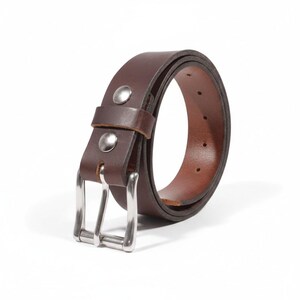 May include: A brown leather belt with a silver-colored buckle and two silver rivets. The belt is rolled up, showcasing its rich color and texture. A classic accessory.
