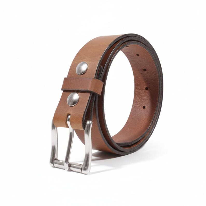 May include: A brown leather belt with a silver-colored buckle and two silver rivets. The belt is curved, showing the inside and outside of the leather. The belt is likely 1.25 inches wide.