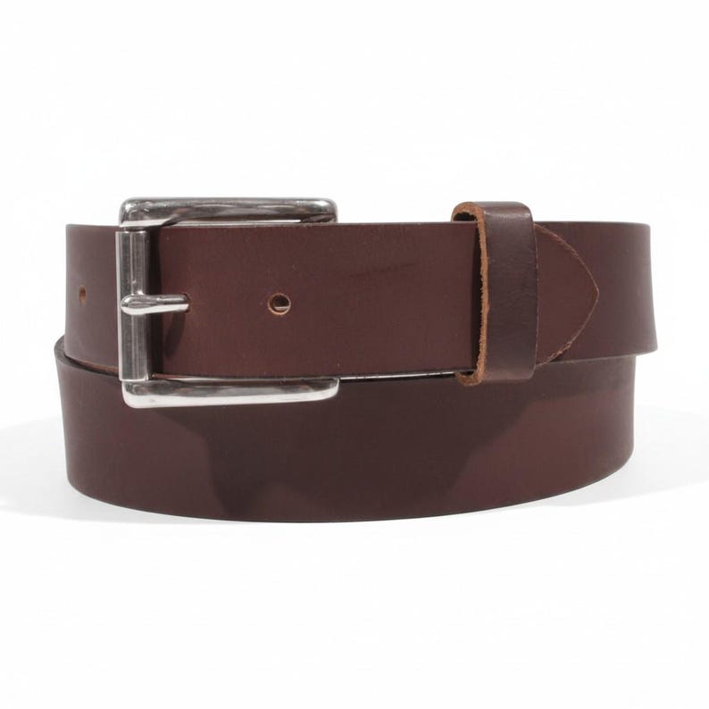 May include: A brown leather belt with a silver-colored buckle. The belt is made of a single piece of leather and has a simple, classic design. The buckle is rectangular and has a polished finish. The belt is approximately 1.5 inches wide.