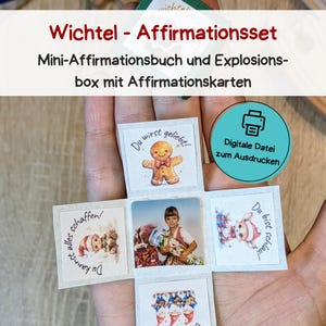 Op de afbeelding: Een kleine, open doos met zes vierkante kaarten, elk met een andere afbeelding en tekst. De bovenkant van de doos heeft de tekst "Wichtel - Affirmationsset". De kaarten hebben afbeeldingen van een peperkoekmannetje, een kind en kerstthema-illustraties.