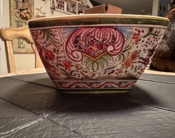 May include: A square ceramic bowl with a hand-painted floral design. The bowl features a cream-colored base with red, orange, and green floral patterns. The rim is trimmed with a green border. The bowl is approximately 12 inches wide.