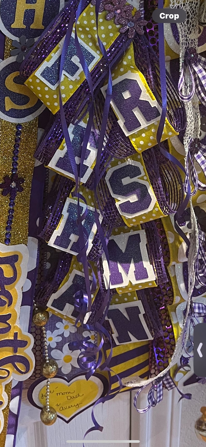 May include: Purple and gold graduation door swag with the letters "H.R.S.A.M.N." and a heart-shaped sign that says "To Mom & Dad Avery".