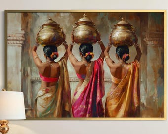 May include: A framed print showing three women in traditional Indian dress, each balancing a golden pot on their head. The women are viewed from behind, wearing colourful saris in pink, yellow, and cream. The artwork is displayed above a wooden desk.