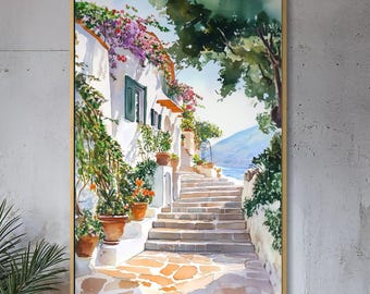May include: A framed watercolor painting depicts a sunlit Mediterranean street scene. White buildings with terracotta pots and purple flowers line a stone staircase. The artwork is displayed on a textured gray wall, with a wooden cabinet and a potted plant in the foreground.