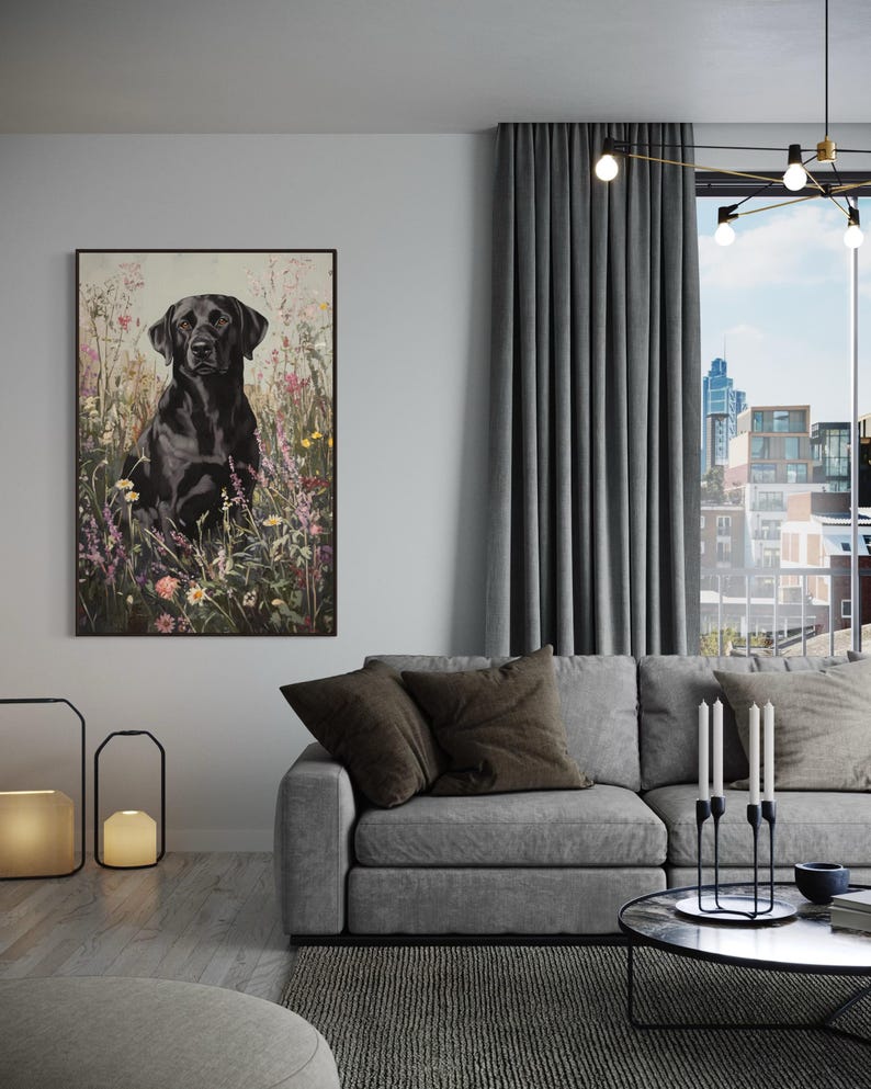 Pode incluir: Um c&atilde;o Labrador Retriever preto sentado em um campo de flores silvestres. O c&atilde;o est&aacute; olhando diretamente para a c&acirc;mera. A imagem est&aacute; emoldurada em uma moldura preta e est&aacute; pendurada em uma parede de uma sala de estar.
