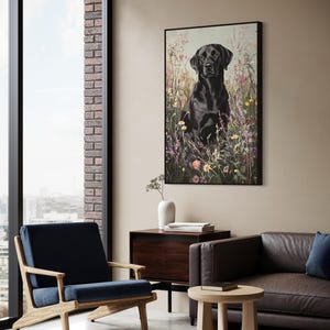 Pode incluir: Um labrador retriever preto sentado em um campo de flores silvestres. O c&atilde;o est&aacute; olhando diretamente para a c&acirc;mera. A pintura &eacute; emoldurada em preto e pendurada em uma parede em uma sala de estar moderna.