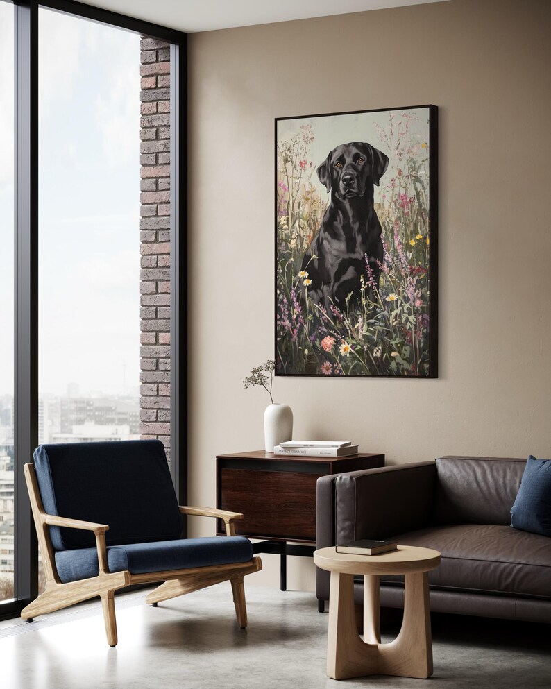 Pode incluir: Um labrador retriever preto sentado em um campo de flores silvestres. O c&atilde;o est&aacute; olhando diretamente para a c&acirc;mera. A pintura &eacute; emoldurada em preto e pendurada em uma parede em uma sala de estar moderna.