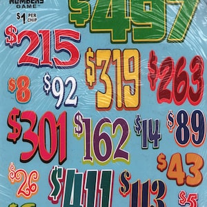 May include: A Crazy Numbers Game board featuring a light blue background with various dollar amounts in different colors and fonts, including $497, $215, $319, $263, $8, $92, $301, $162, $14, $89, $26, $411, $113, $43, $6, and $5, all encased in clear plastic.