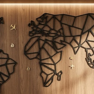Puede incluir: Un mapa del mundo geométrico negro como arte de pared con un diseño de estructura de alambre de los continentes. El mapa incluye pequeños iconos decorativos de color dorado de aviones y veleros dispersos por toda la superficie.