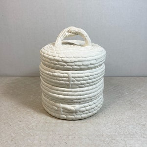 May include: White ceramic jar with a woven rope design and a lid with a rope handle.