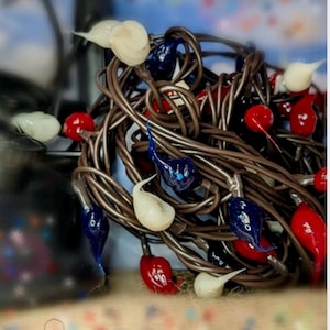 May include: A tangled string of Christmas lights with red, white, and blue bulbs. The lights are in a variety of shapes and sizes.