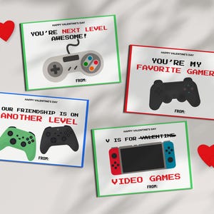 May include: Four Valentine's Day cards with gaming themes. Each card has a different message in red and white text, such as "You're Next Level Awesome!" and "You're My Favorite Gamer." The cards feature controller graphics and are framed in green, red, and blue. Two red heart cutouts are also present.