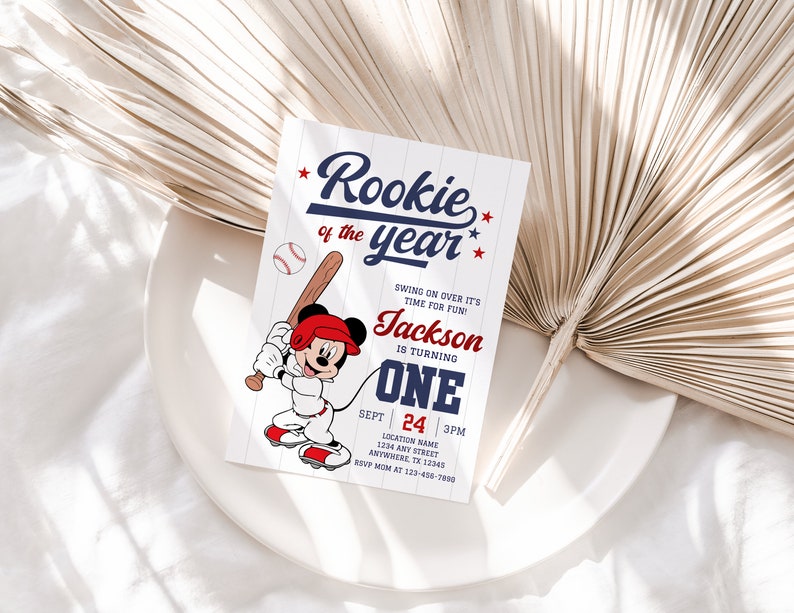 May include: A baseball-themed birthday invitation with a cartoon Mickey Mouse character holding a bat. The invitation says "Rookie of the year" and includes the name "Jackson" and the age "One".