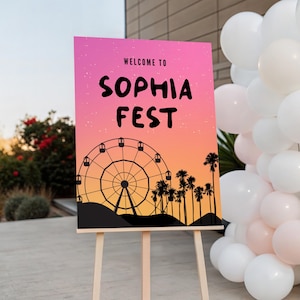 Puede incluir: Un letrero sobre un caballete de madera con el texto "WELCOME TO SOPHIA FEST" sobre un fondo degradado rosa y naranja. El diseño incluye una noria y palmeras en silueta.
